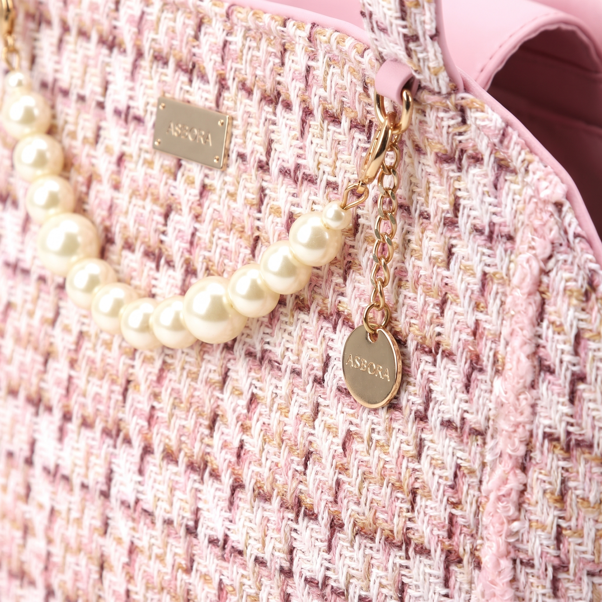 Macro detail of tweed weave, pearl chain and gold charm on the Coquette cat carrier