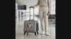 Woman standing with the Orbit space-capsule cat carrier at an airport, cat looking out the bubble window